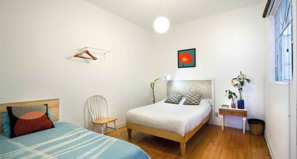 Simpele slaapkamer met twee bedden in Casa Indigo Mexico City