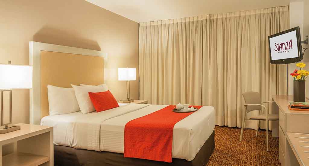 Stijlvol bed met oranje accent in Stanza Hotel Mexico City